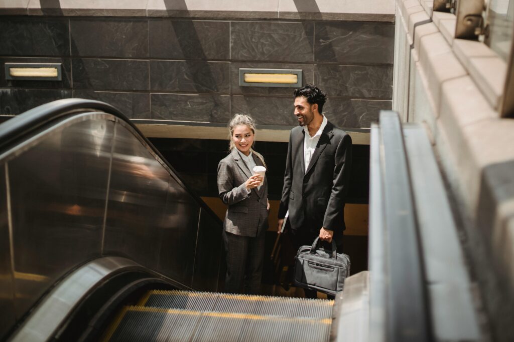 The Future of Vertical Transportation: Data-Driven Decisions a man and a woman on an escalator going up. the woman is blonde and holding a cup and they are dressed in business attire