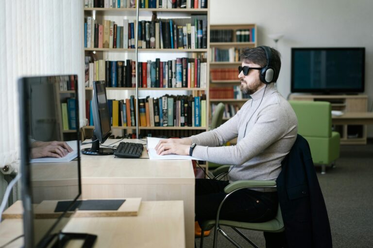 Accessibility Statement man with glasses using a braille keyboard at a desktop in a brightly lit office